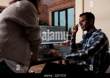 Software developers sitting at desk and developing a functional data encryption system. Multiethnic cyber security team members in agency office writing cloud database processing algorithm. Stock Photo