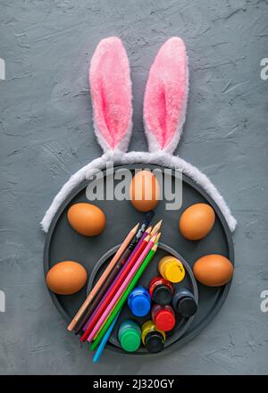 Multicolour paints and brushes on the plate with eggs. Colouring eggs for easter holiday concept. Stock Photo