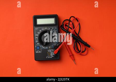 Black multimeter on orange background, top view Stock Photo