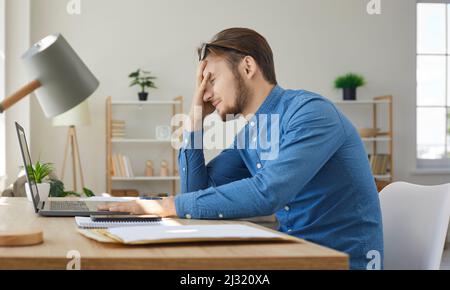 Tired, stressed, frustrated young man having problem while working on his laptop Stock Photo