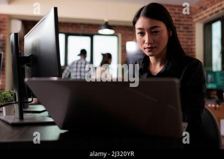 Asian software developer engineering an autonomous defence system using advanced artificial intelligence technology. Cyber officer encrypting big chunks of data in order to secure important files. Stock Photo