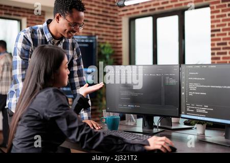 Programmers questioning source of cyber attacks and system security coverage. Software technician triangulates hacker location by updating safety script codes and data processor sequencer. Stock Photo