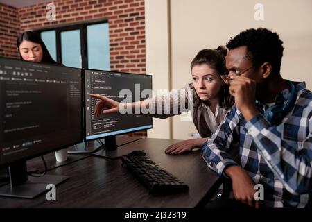 Caucasian software developer signaling on screen data breach and deactivated security system. Tech engineer observing multiple system security breaches caused by overloaded storage servers. Stock Photo