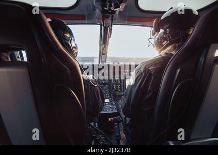 Pilot and copilot seated in a helicopter cockpit during flight Stock Photo