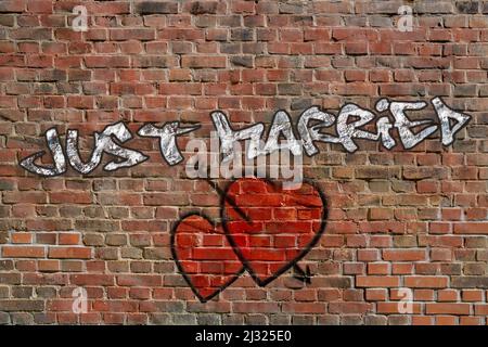 Silver Just Married graffiti with to sprayed red hearts on red brick wall Stock Photo