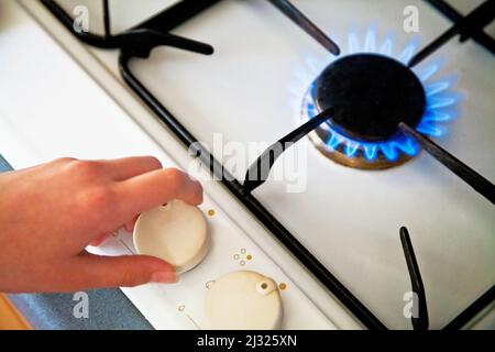 Hand turning down the gas ring on a hob Stock Photo