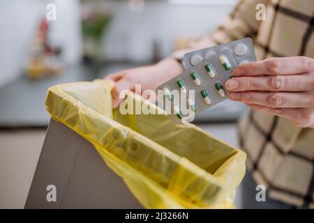 Woman's hands holding and throwing expired pills to the trash bin. Stock Photo