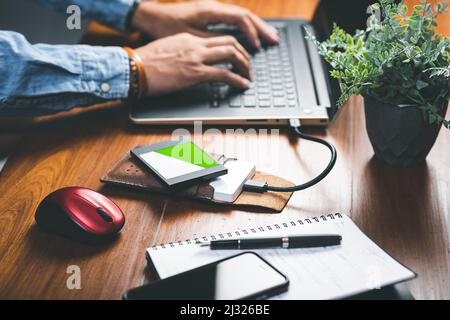 Closeup external hard drive and internal solid state drive on wooden desktop. Working with external hard drive. Stock Photo