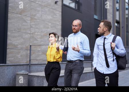 Team of economist managers or real estate agents in casual clothes going outdoor. Discussing project, presentation, talking or brainstorming. Business or finance industry concept. High quality image Stock Photo