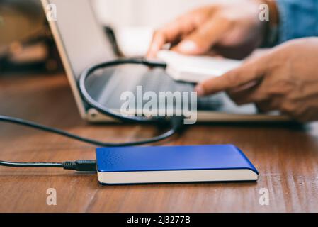 Closeup external hard drive on wooden desktop. Working with external hard drive. Stock Photo