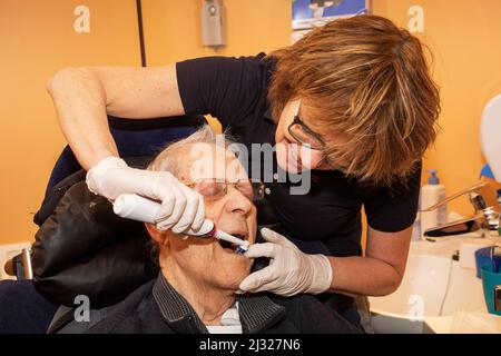 Netherlands, Gendt - Nurse in a care home for elderly is brushing the teeth of a resident. Stock Photo