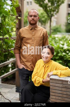 Young confident business colleagues standing outside office building looking forward. Team of finance managers, economists or real estate agents in casual clothes outdoors. High quality image Stock Photo