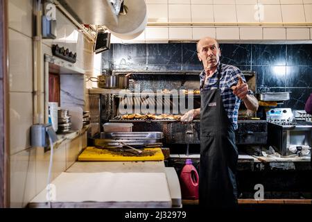Faro, Portugal - March 11, 2022: Experienced man grilling the best chicken in the city in Churrasqueira Receife Stock Photo