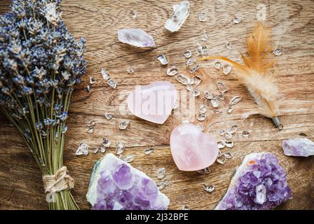 Above view of two polished pink color rose quartz crystals on wood tray in home. Attract love, healing heart chakra concept. Bouquet of dried lavender Stock Photo