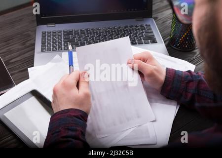 Young businessman or freelancer working with documents and with laptop and smartphone, remote office Stock Photo
