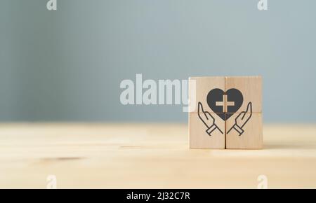 Life & health insurance services. Business hands holding heart shape on wooden cubes on beautiful grey background and copy space. Use for banner in in Stock Photo