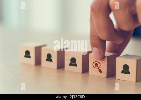 Human resources and recruitment concept. Employment headhunting concept. Choice of an employee leader from the crowd. Man holds wooden cube with findi Stock Photo