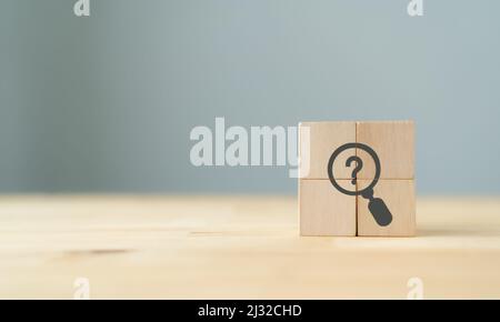 The concept of finding solutions, true or false. Answers on questions. The wooden cubes with magnifying glass and question marks symbols on beautiful Stock Photo