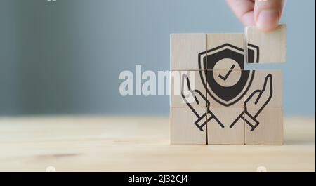 Work safety concept, hazards, protections, health and regulation.  Concept of data security. Hand holds wooden cubes with hand holding protect shield Stock Photo
