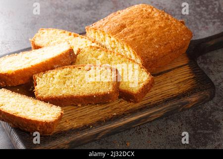 Tasty Madeira sponge cake closeup served on a wooden cutting board on the concrete table. Horizontal Stock Photo
