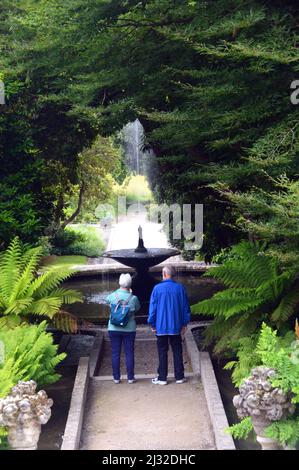 A Couple Looking at the Fountain below the Steps to Neptune's Statue & Water Cascade at Holker Hall & Gardens, Lake District, Cumbria, England, UK. Stock Photo