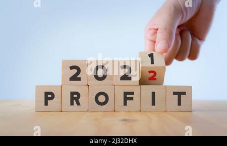 Business profit plan concept in 2022 . Build a profit and financial plan. Hand flip wooden cubes 2021 to 2022 with text "PROFIT" on white background a Stock Photo