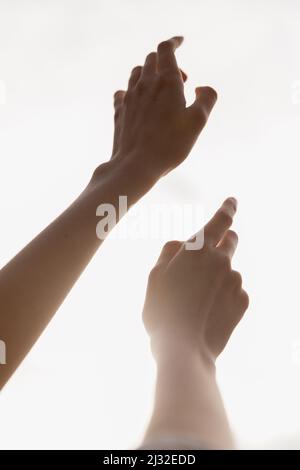 Two hands and arms reach upwards towards the sky, an image of faith, healing, hope Stock Photo