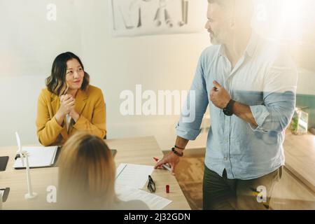 Mature mechanical engineer sharing his creative ideas during a meeting in a boardroom. Group of innovative businesspeople planning a project on renewa Stock Photo