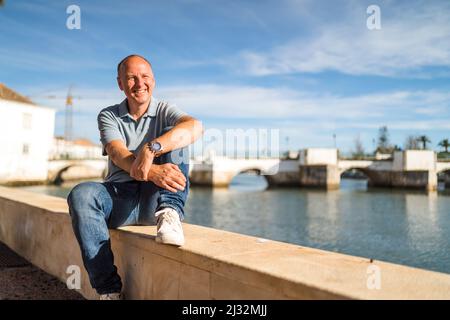 Portrait of smiling man relaxing by the riverbank in touristic and historic Tavira, Algarve, Portugal Stock Photo