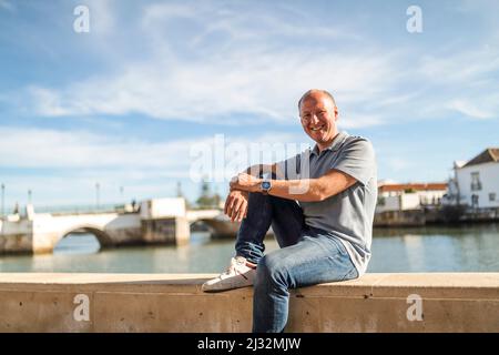 Portrait of smiling man relaxing by the riverbank in touristic and historic Tavira, Algarve, Portugal Stock Photo
