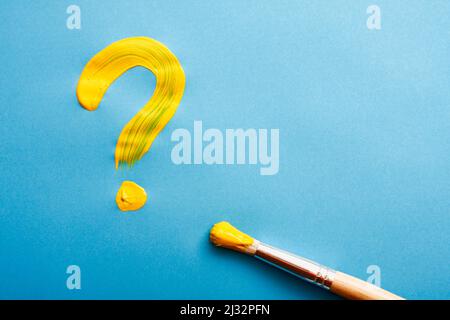 Yellow question mark written with oil paint on blue. Stock Photo
