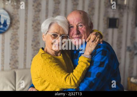 Portrait of an Caucasian European elderly couple smiling and embracing in vintage home interior. High quality photo Stock Photo