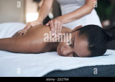 You deserve this and more. Shot of a young woman getting a back massage at a spa. Stock Photo