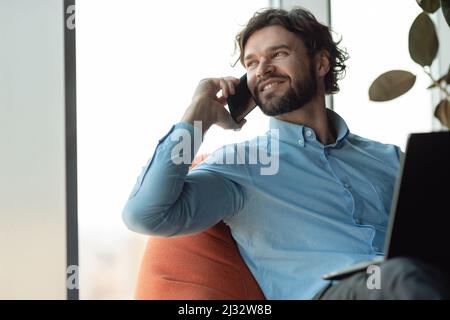 Smiling man working and talking on phone at office Stock Photo