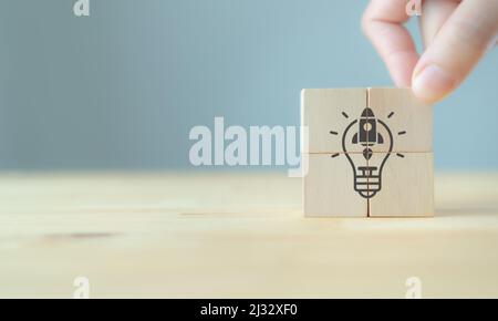 Launching idea, startup business concept. Beyond competitors, good plan, successful goal concept. Hand holds wooden cubes with 'rocket launch' icon on Stock Photo