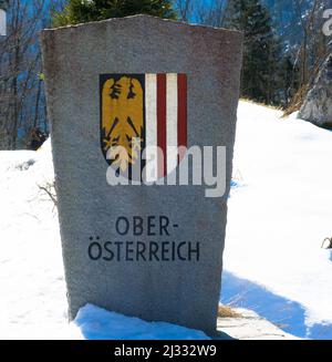 Stone border post of Upper Austria with its coat of arms in winter landscape with snow. Stock Photo