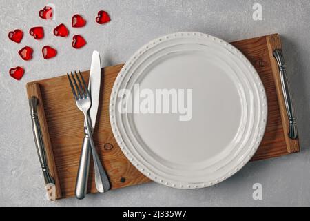 Empty white plate with cutlery on a wooden tray on a light gray concrete table Stock Photo