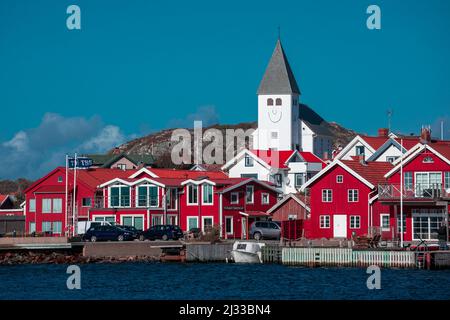 Red houses with a church in the village of Skärhamn on the archipelago island of Tjörn on the west coast of Sweden, blue sky with sun Stock Photo