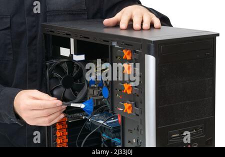 Service center employee wearing black uniform using a brush to dust off internals of a personal computer. Stock Photo