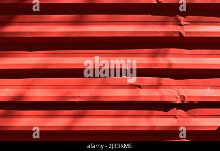 Red corrugated metal plate surrounding wasteland Stock Photo