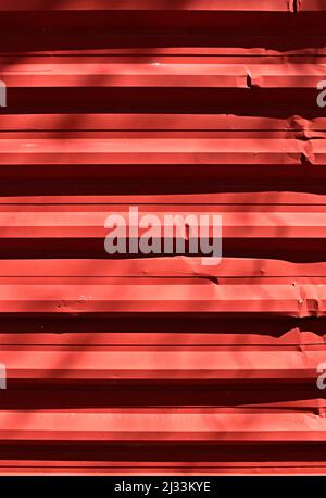 Red corrugated metal plate surrounding wasteland Stock Photo