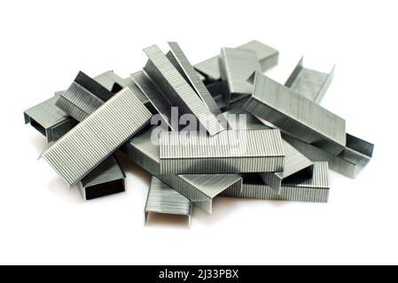 Staples from a stapler on a white background. Isolate of a bunch of staples scattered on the surface Stock Photo