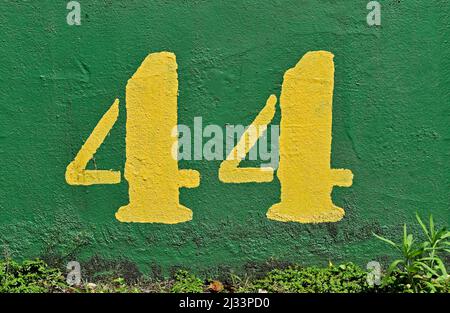 Number 44 painted in yellow on a green wall Stock Photo