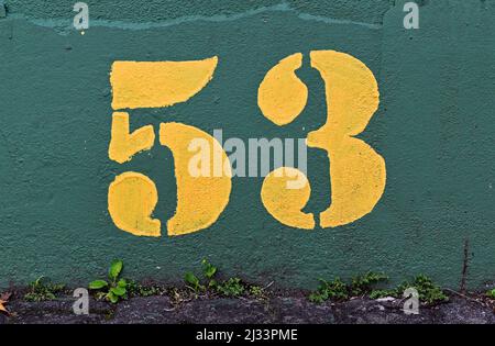 Number 53 painted in yellow on a green wall Stock Photo