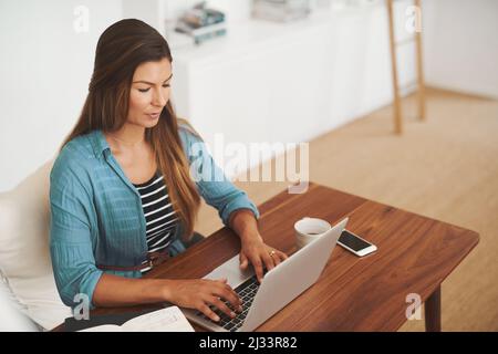 Working from the comfort of home. Shot of a focussed freelancer using her laptop while working from her office at home. Stock Photo