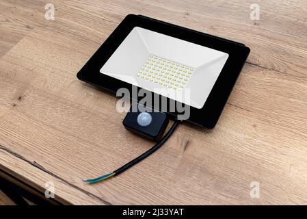 Outdoor LED lamp with a motion sensor composed of seventy LEDs lying on a table with cut cables. Stock Photo