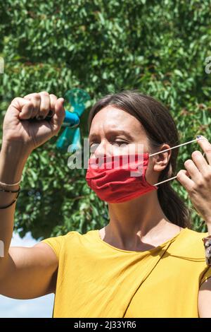 using hand held ventilator to cool down a virus protective face mask Stock Photo