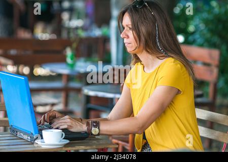 young woman using laptop in outdoor coffee shop table Stock Photo