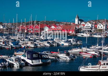 Harbor and red houses with church in the village of Skärhamn on the archipelago island of Tjörn on the west coast of Sweden, blue sky with sun Stock Photo