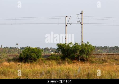 View of the Indian railway line along with overhead electrical wires. Selective focus on pole. Stock Photo